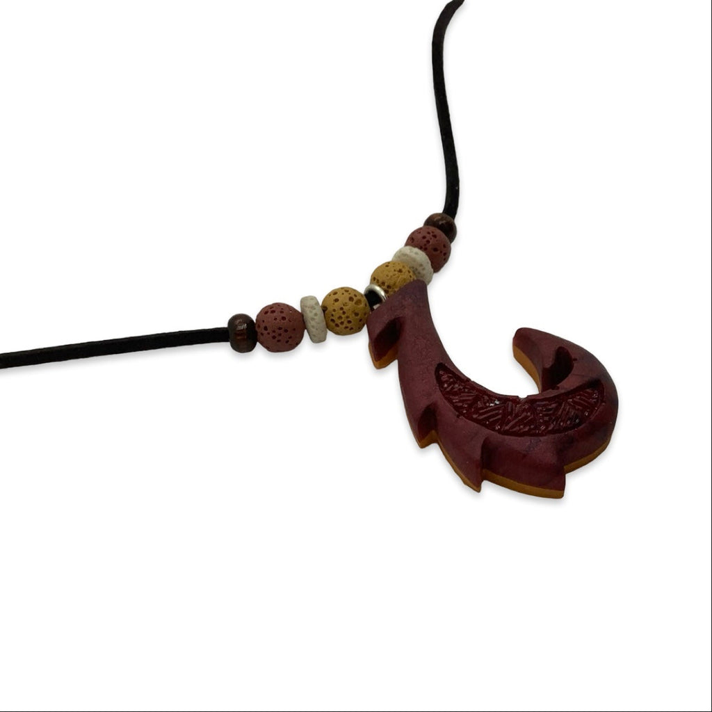 Bronze and orange fish-shaped pendant on a black cord with beads against a white background