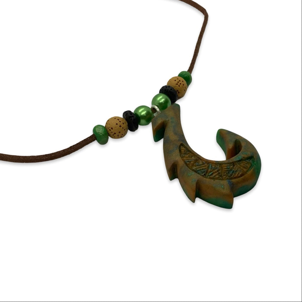 Necklace with a hook-shaped pendant and green beads on a white background