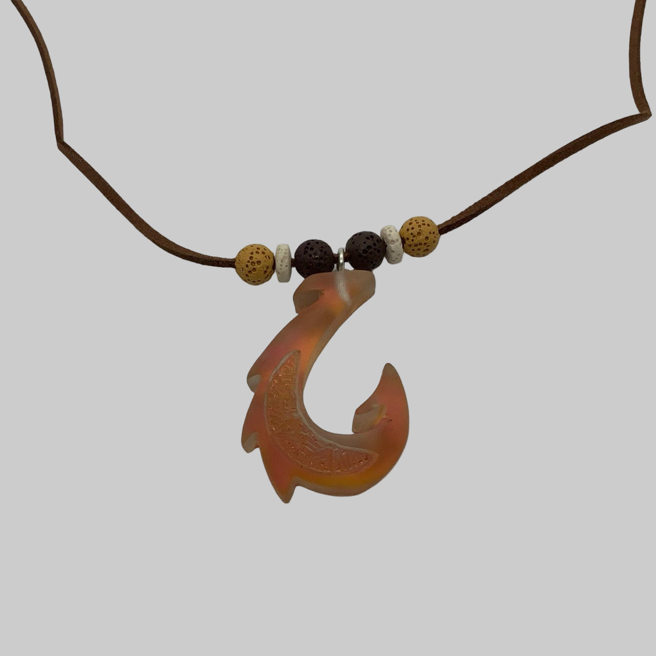 Chameleon Gold fish hook pendant on a cord with beads against a white background