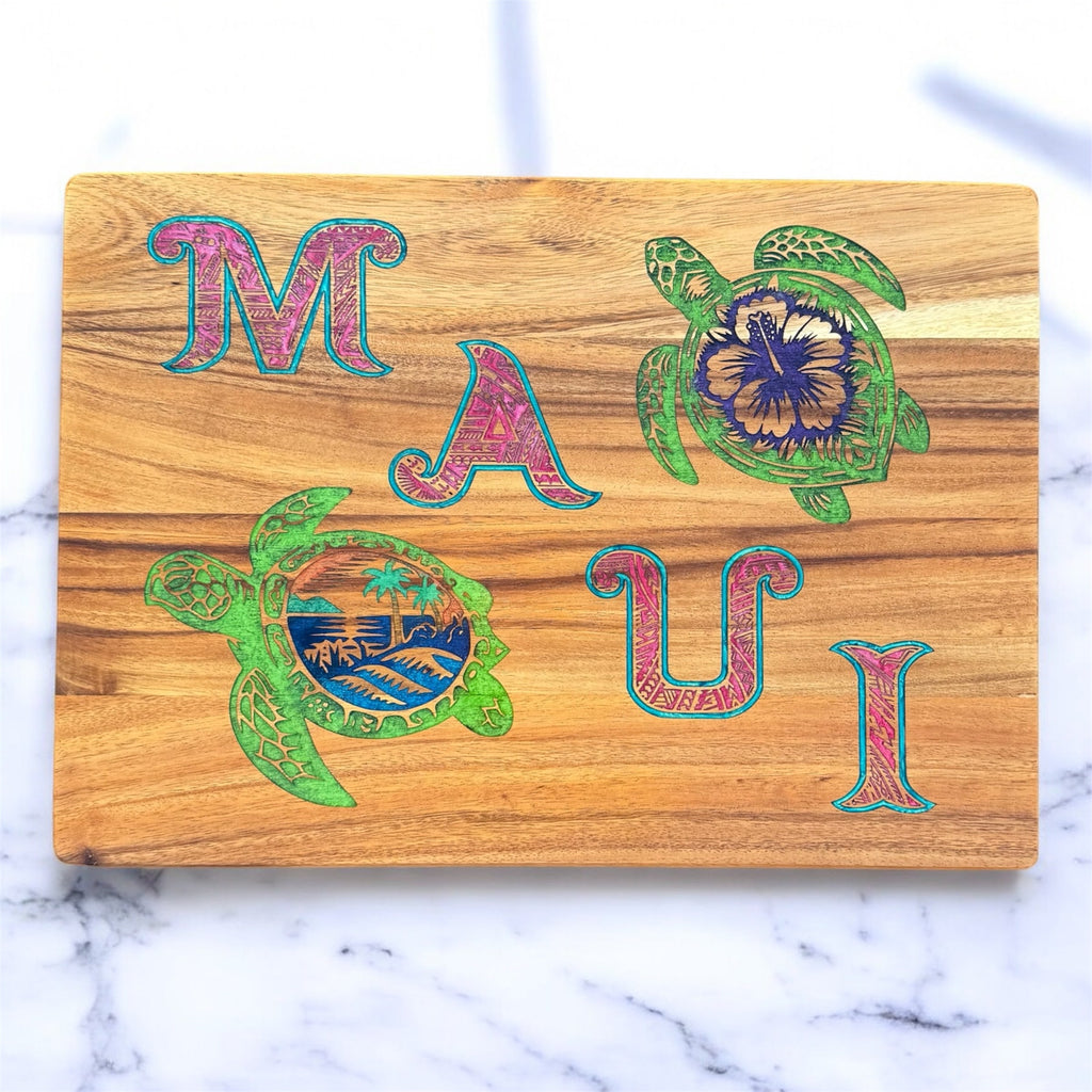 Wooden cutting board with 'MAUI' and turtle designs on a marble background