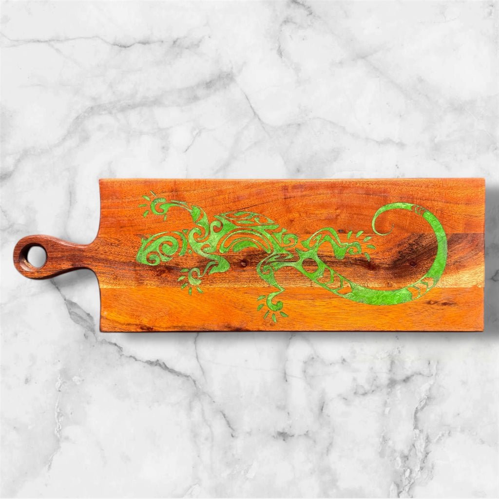 Wooden cutting board with green lizard design on a marble surface