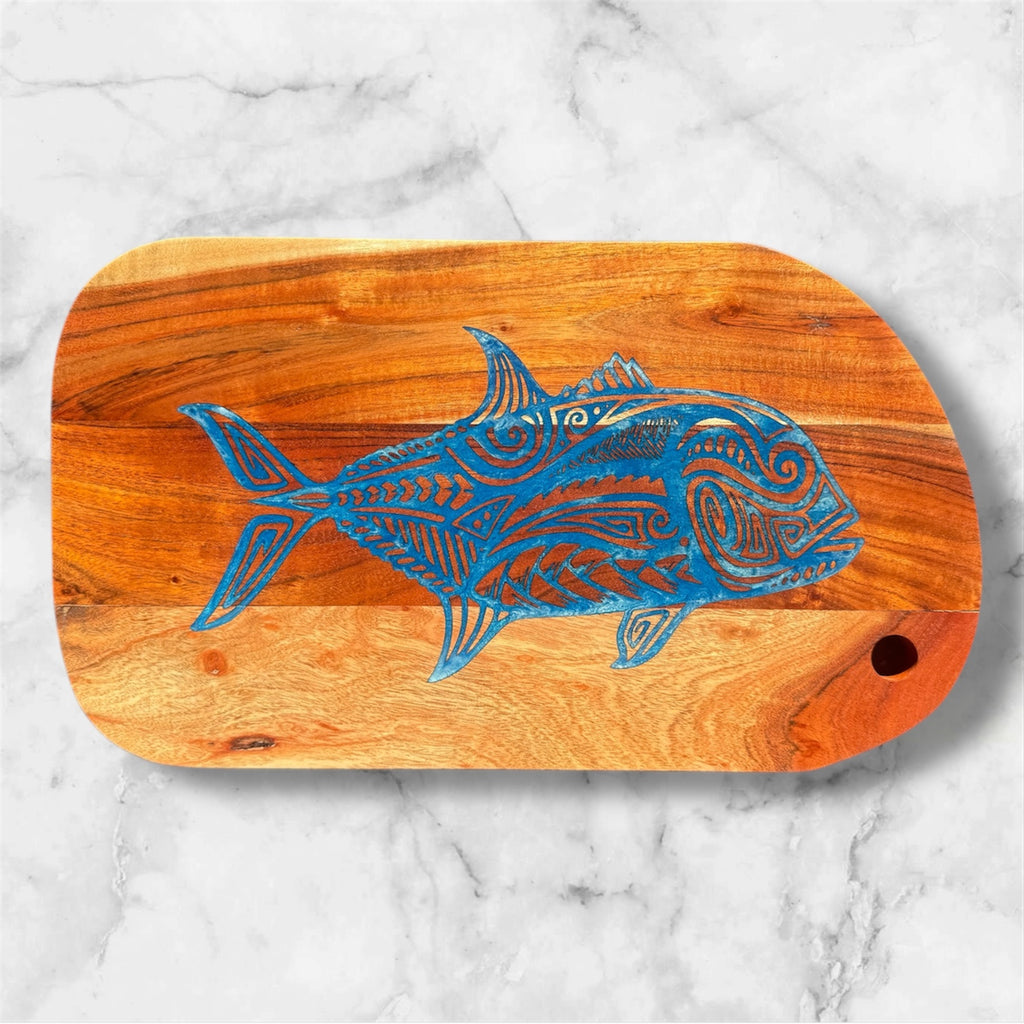 Wooden cutting board with blue fish design on a marble background
