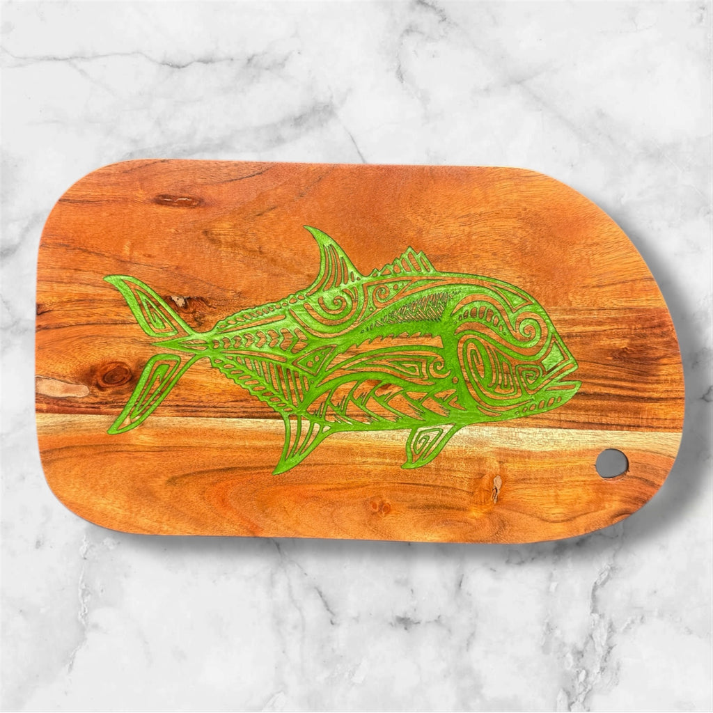 Wooden cutting board with green fish design on a marble background