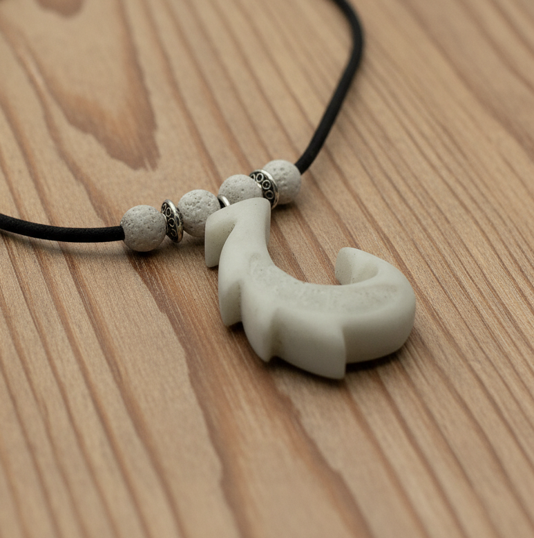 Necklace with a white hook pendant and beads on a wooden surface
